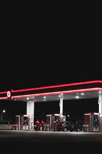 A brightly lit gas station in Mexico captured at night with neon lights and parked cars.