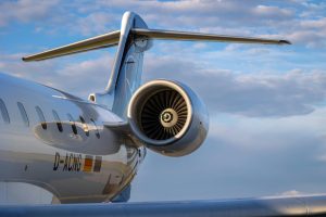 Detailed view of a jet engine and tail against a blue sky with clouds.