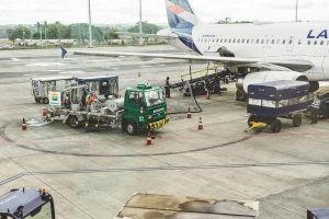 Ground support services in action at an airport terminal with visible aircraft and service vehicles.