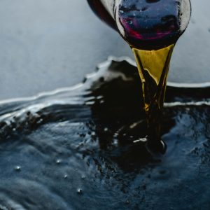 Close-up of red wine being poured and spilling on a dark surface, creating a dramatic scene.